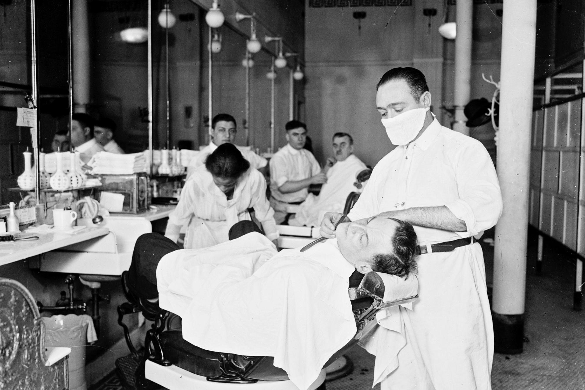 Een barbier behandelt een klant in Chicago in 1918.