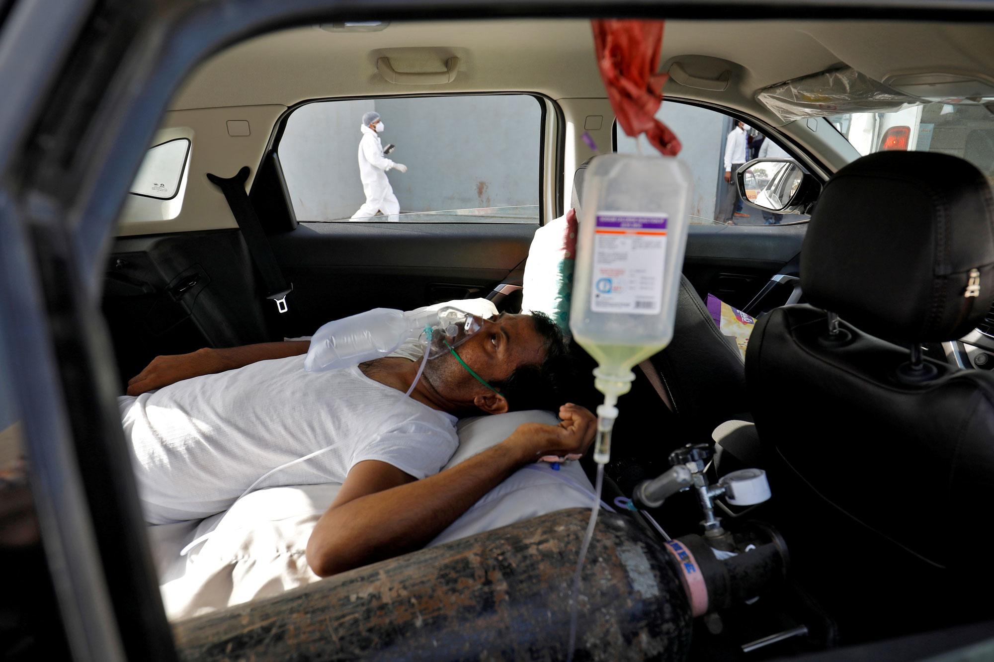 Een man met ademhalingsproblemen wacht in een auto voor opname in een ziekenhuis.