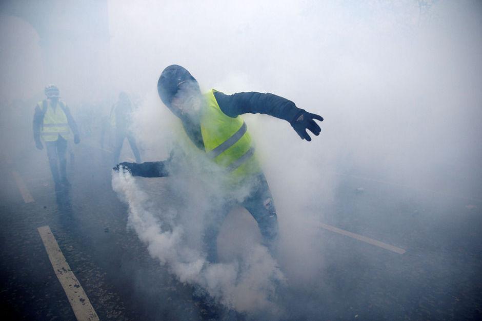 Een betoger gooit een traangasgranaat terug naar de politie, 1 december 2018.