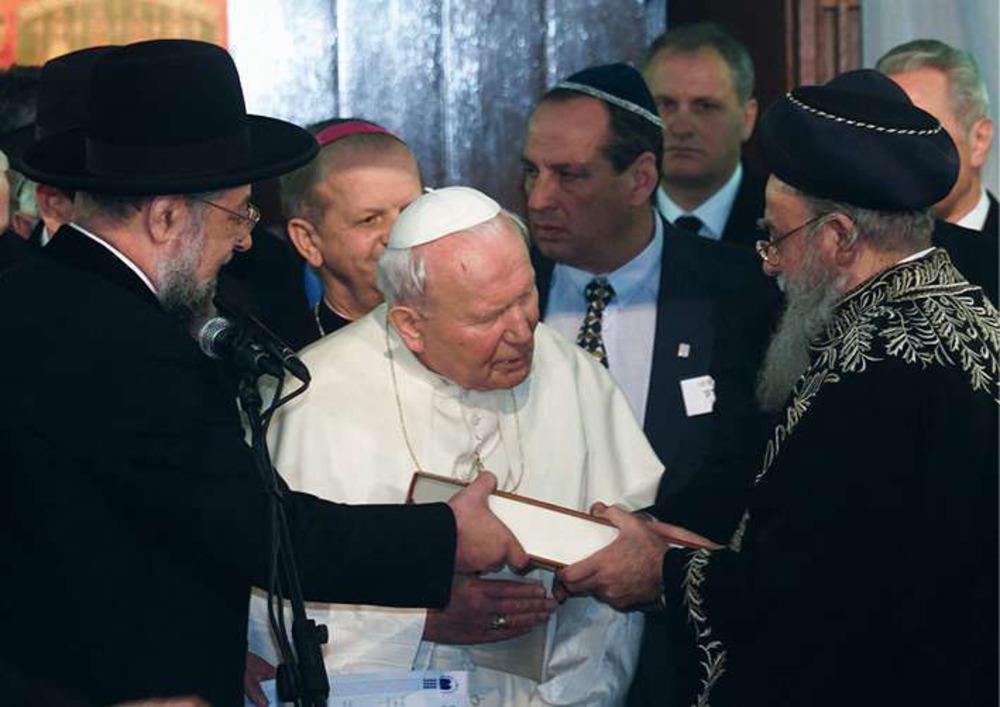 Jeruzalem, 23 maart 2000. De Asjkenazische opperrabbijn van Israël, Yisrael Meir Lau (links), en de Sefardische opperrabijn van Israël, Eliyahu Bakshi-Doron (rechts), schenken paus Johannes Paulus II een bijbel.