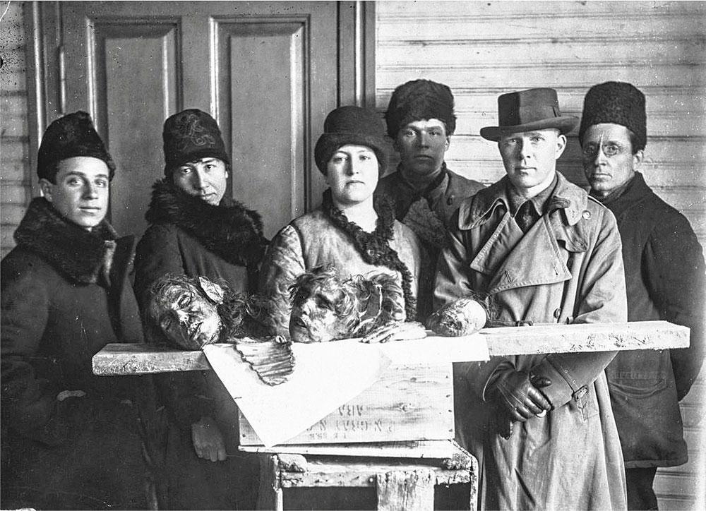 Henry Wolfe van de ARA (2e r.) poseert met Sovjetfunctionarissen bij de resten van een kannibalenmaal.