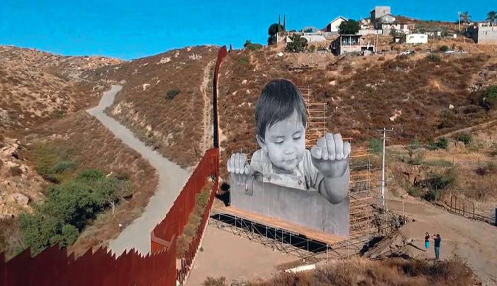 Dit reclamebord bij de Mexicaanse stad Tecate aan de grens met de VS is een installatie van de Franse kunstenaar JR. het kwam enkele dagen nadat president Trump het DACA-programma had stopgezet. DACA bood zo'n 800.000 kinderen van immigranten zonder papieren bescherming tegen uitwijzing. 