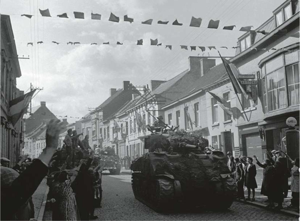 Lessines, september 1944: Belgische burgers wuiven naar de Britse tanks. De vlaggen hangen uit bij de bevrijding.