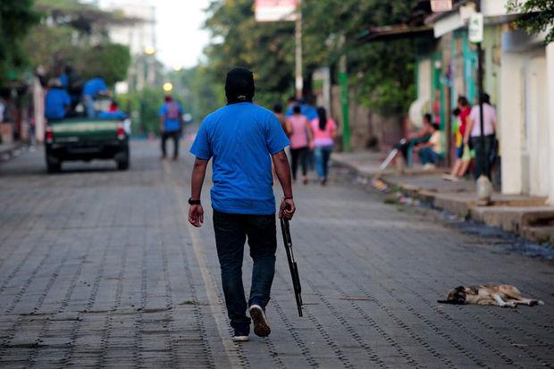 Een manifestant die de overheid steunt loopt over straat met een shotgun na clashes met betogers in Masaya, Nicaragua, 17 juli 2018.