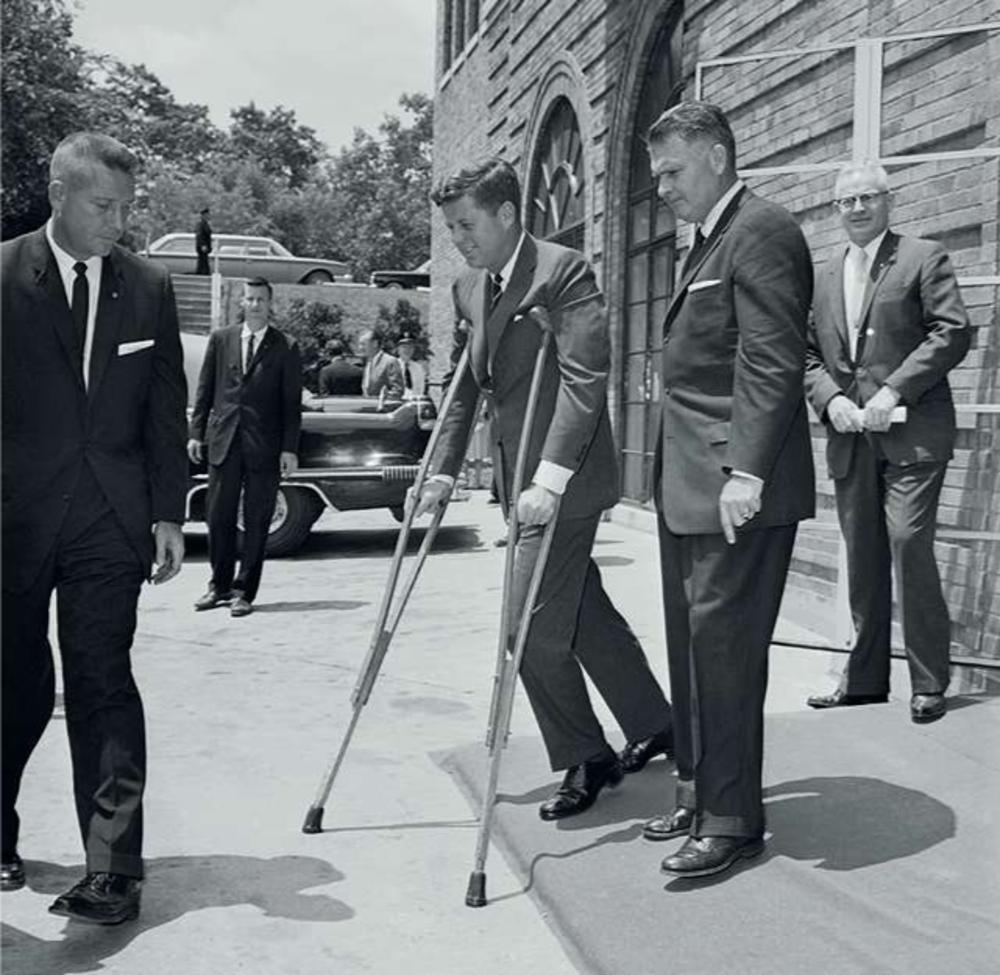 President John Kennedy verlaat op krukken een vergadering in Washington.