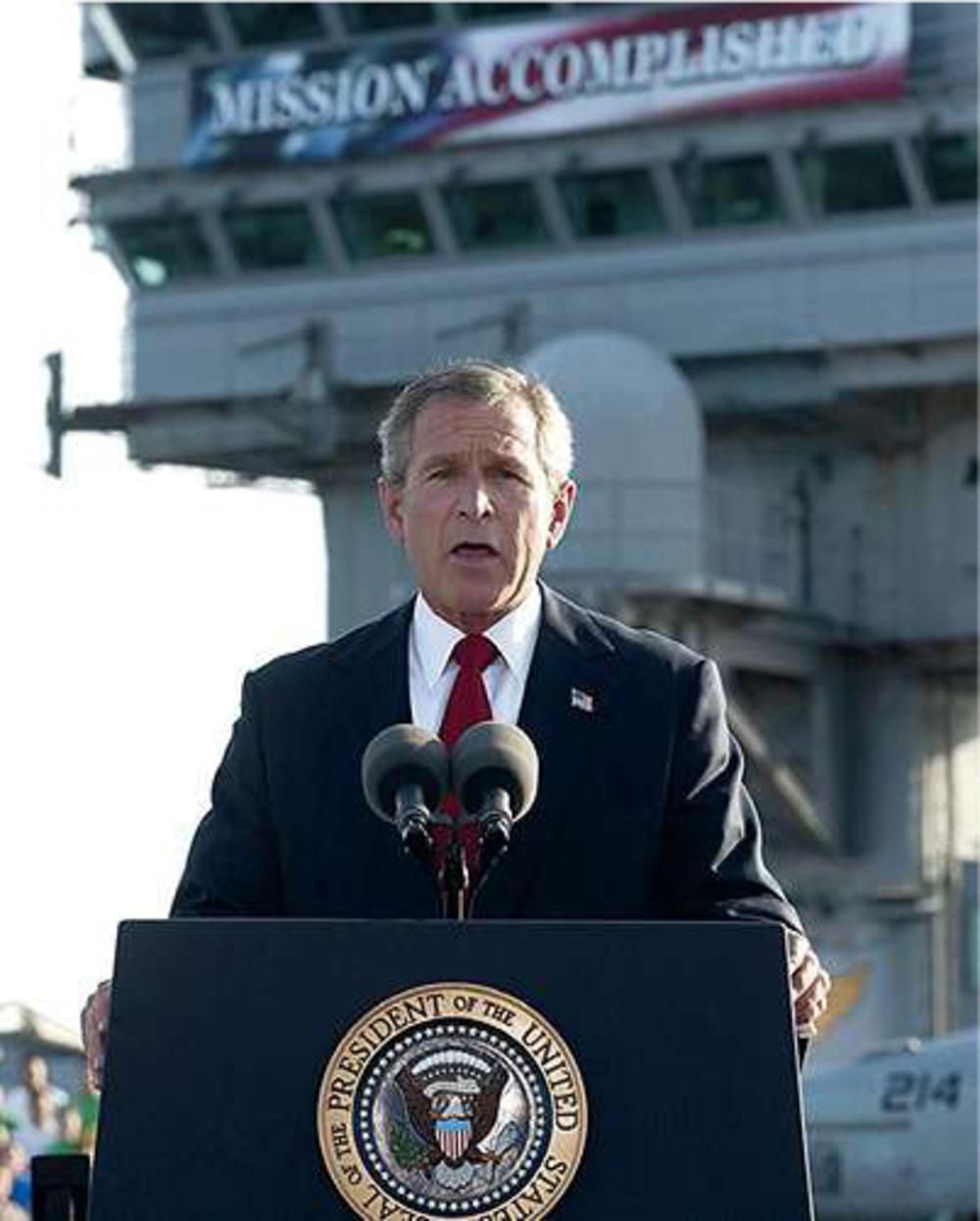 President George Bush op 1 mei 2003. Achter hem hangt een spandoek: 'Mission Accomplished'. De ramp in Irak moet dan nog beginnen.