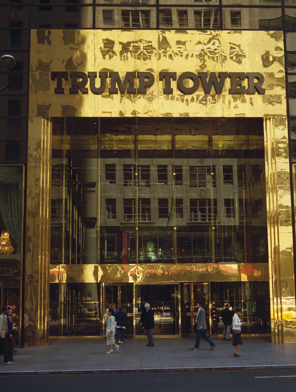 De ingang van Tramp Tower op Fifth Avenue in New York. 202 meter hoog. Het aantal verdiepingen is kunstmatig met 10 stuks opgedreven. Want: hoe hoger, hoe grootser, prestige.