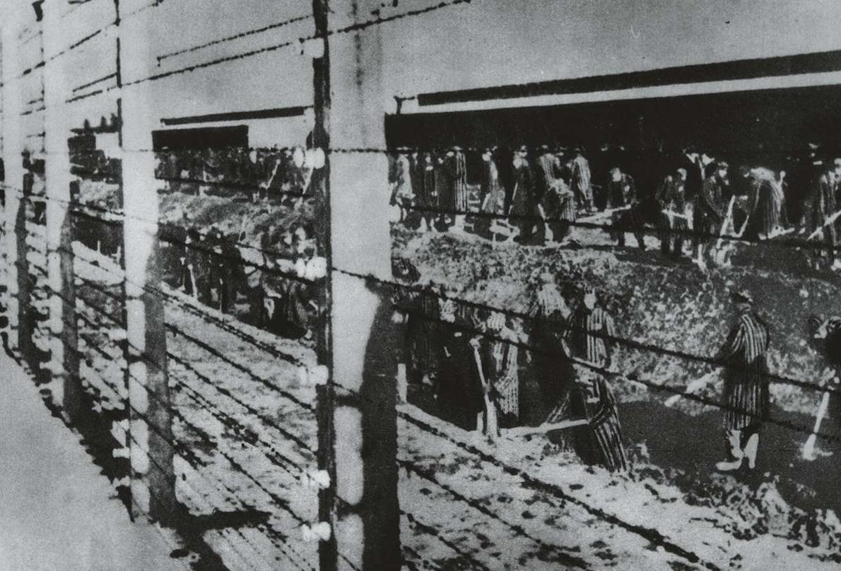 Auschwitz, 1940: achter hekken met elektriciteitsdraad onder stroom graven gevangenen een greppel.