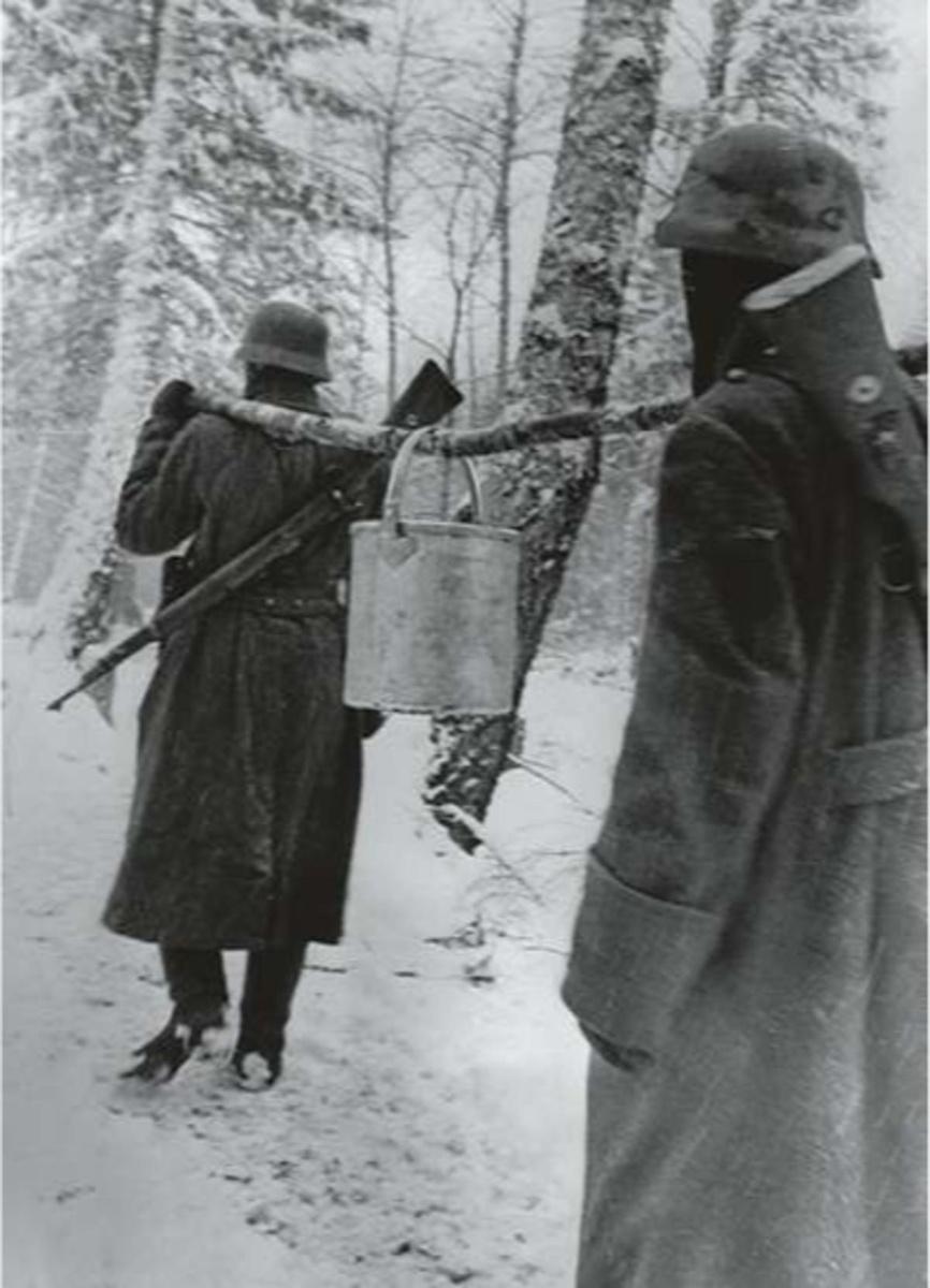15 december 1942: frontsoldaten dragen een emmer water door een besneeuwd bos in volle winter aan het Russische oostfront.