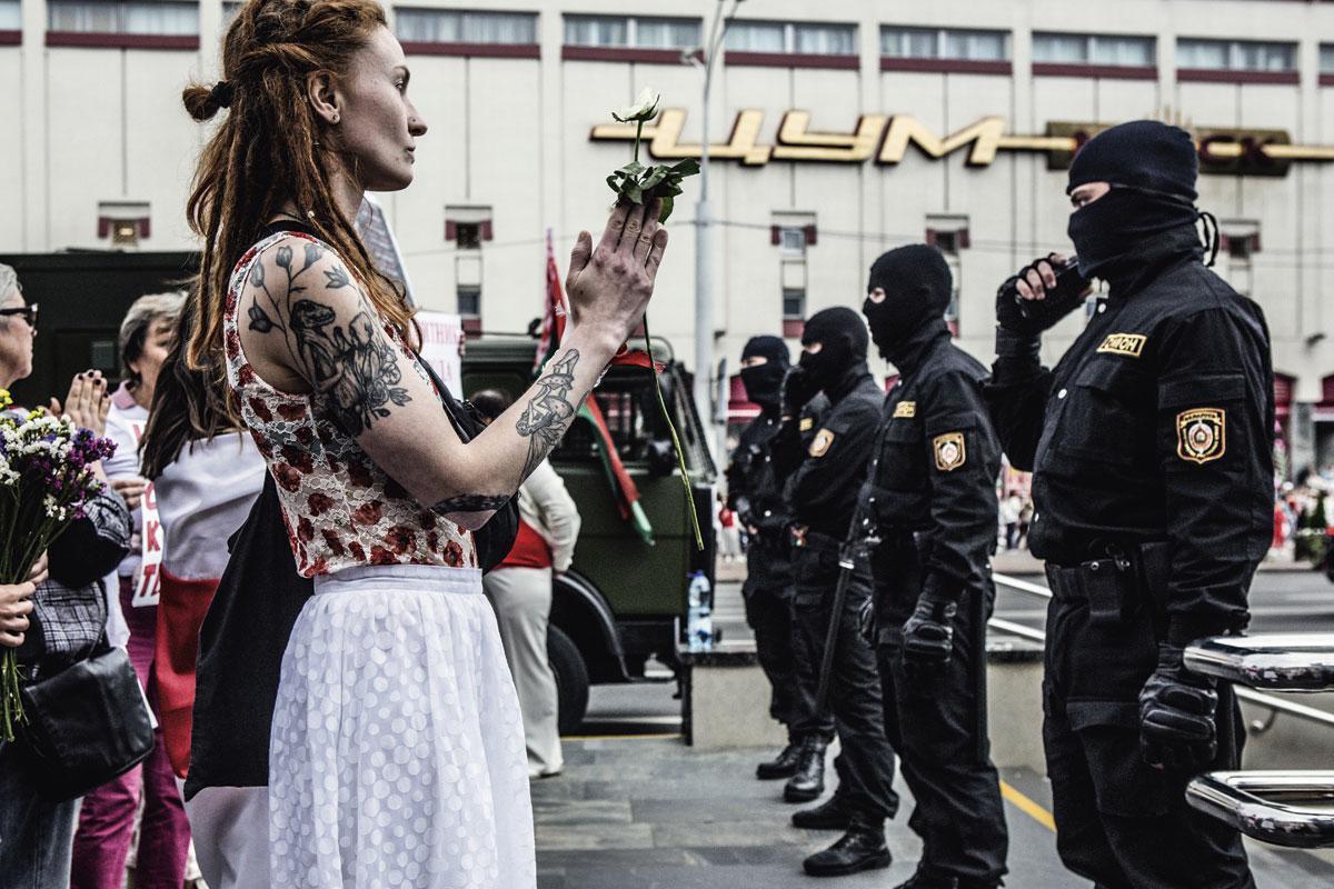 Een demonstrante staat met een witte bloem, symbool van vrede, voor leden van de OMON, de beruchte Wit-Russische oproerpolitie.