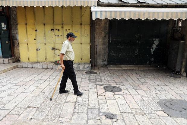 Een Palestijn wandelt voorbij gesloten winkels tijdens de nationale staking.