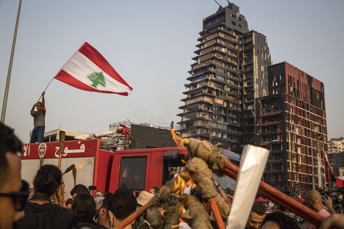Deelnemers van de herdenkingsmars steken fakkels aan als eerbetoon aan de brandweerlui en de overlevenden van de explosie. In de andere hand bungelt een strop - symbolisch hangen ze Libanese politici op.