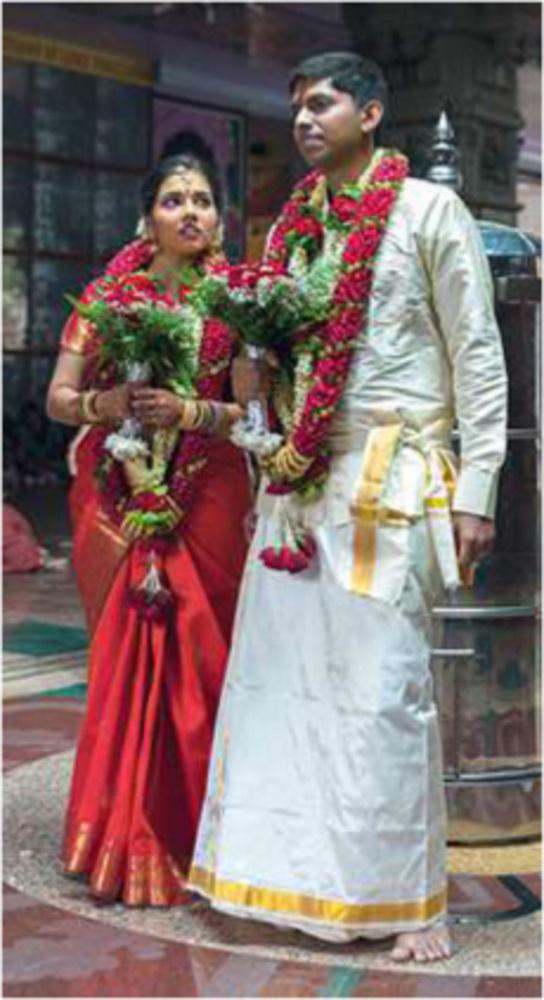 In de hindoe-tempel Sri Senpaga Vinayagar in Singapore dragen bruid en bruidegom bloemenkransen en bruidsboeketten. Blootvoets, de vrouw in rood, de man in wit.