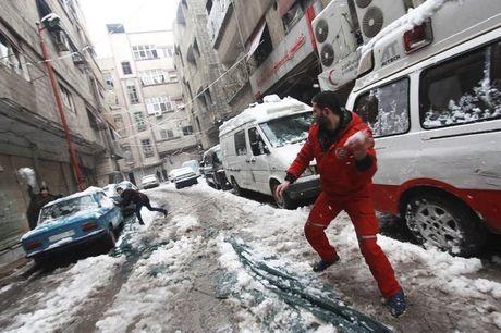 Medewerker van het Arabische Rode Kruis speelt in de sneeuw met Syrische kinderen 