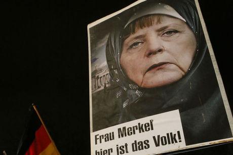 Een bewerkte foto van bondskanselier Angela Merkel in hijab, tijdens een anti-immigratiebetoging van PEGIDA in Duitsland.