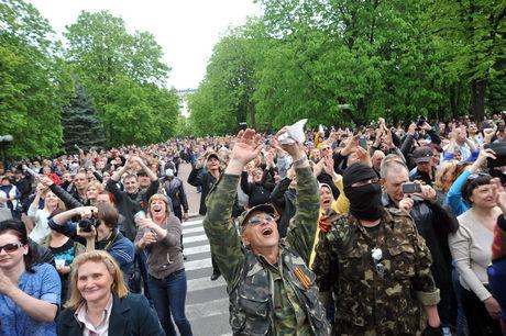 Pro-Russische activisten juichen als gewapende mannen een Oekraïens gebouw in Loegansk binnendringen.