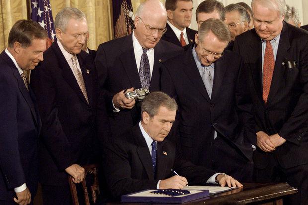 Amerikaans president George W. Bush ondertekent op 26 oktober 2001 de eerste Patriot Act. Rechts, met rode das, Republikeins senator Jim Sensenbrenner, co-auteur van de wet.