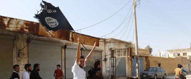 Een man zwaait met een vlag van de Islamitische Staat en viert dat de terreurbeweging de controle over de luchtmachtbasis van de Syrische stad Tabqa heeft verworven.