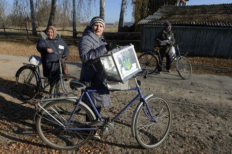 Een medewerker van een verkiezingscommissie heeft een mobiele verkiezingskoffer vast op weg naar lokale kiezers in Horodyshche bij Chernihiv. 