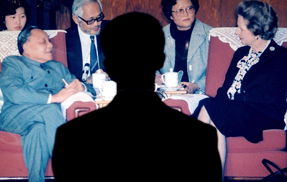 Tijdens een tentoonstelling kijkt een man naar een foto van Deng Xiaoping en Margaret Thatcher. De ontmoeting vond plaats om de overdracht van Hongkong te bespreken.