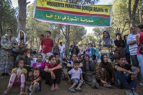 Mannen, vrouwen en kinderen onder een YPG-banner: 