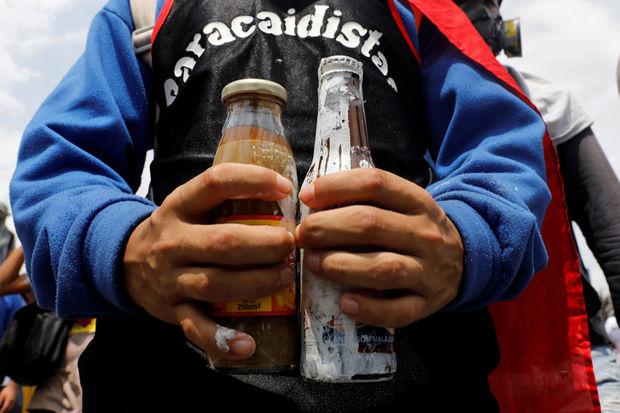 Een betoger met een verfbom (links) en een poopootov-cocktail (rechts) of een fles gevuld met uitwerpselen, 10 mei 2017.