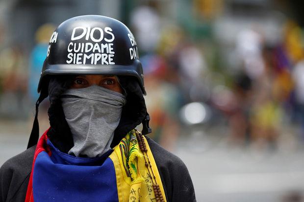 Een betoger draagt een helm met het opschrift 'God zorgt altijd voor me' tijdens een betoging tegen president Maduro, Caracas, 1 juli 2017.