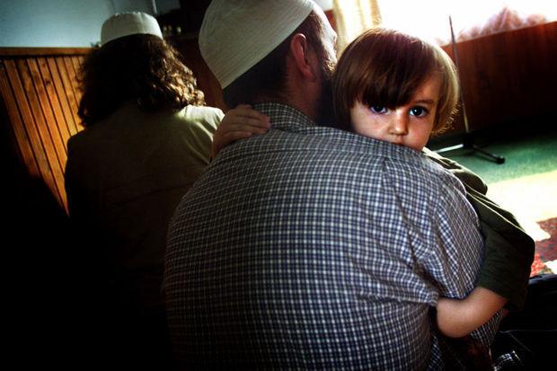 Een Bosnische moslim houdt zijn dochter vast tijdens het gebed in een kleine moskee in Gornja Maoca.