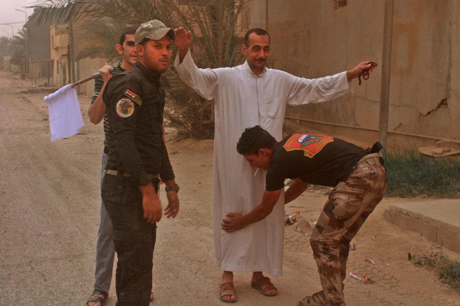 Iraakse regeringstroepen controleren een burger in Al-Qaim na de herovering van de stad op IS (6 november 2017)