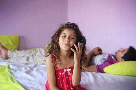 Rojda Nasro op het bed waar haar vader Mohamed uitrust na een werkdag in het naaiatelier. 
