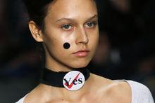 Een model draagt een 'yes'-badge tijdens een modeshow van Vivienne Westwood.