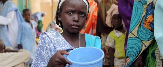 Een meisje staat in de rij voor water, dekens en voedsel die soldaten uit Niger in Damasak uitdelen
