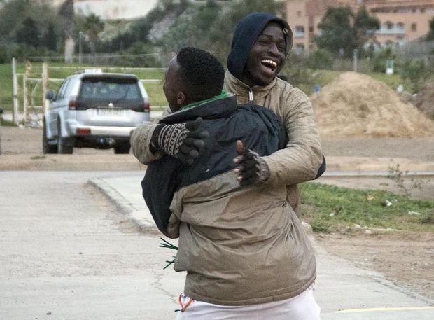 Afrikaanse migranten omhelzen elkaar nadat ze de grens van Melilla hebben overgestoken 