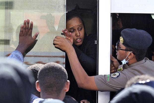 Een Ethiopische huishoudhulp spreekt met een lid van de Saudische veiligheidstroepen terwijl ze in een bus wacht om gerepatrieerd te worden, Riyad, 11 november 2013. Duizenden Afrikaanse arbeidsmigranten wilden gerepatrieerd worden nadat er doden vielen bij een controle door de Saudische autoriteiten.
