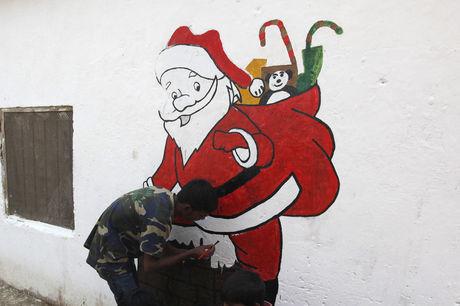 Een jongen schildert de kerstman op een muur in Karachi, Pakistan.