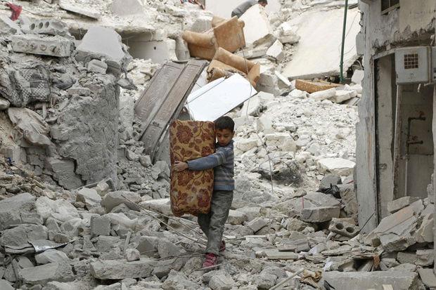 Een jongetje loopt over het puin van verwoeste gebouwen in Aleppo, Syrië.