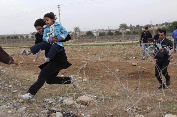 Syrische vluchtelingen springen over prikkeldraad nabij de Turkse grens