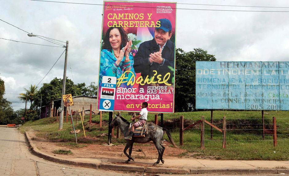 Een jongen rijdt op zijn paard voorbij een billboard dat presidentskandidaat Daniel Ortega en zijn echtgenote en vice-presidentskandidaat Rosario Murillo aanprijst.