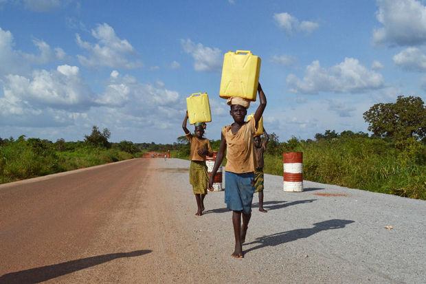Meisjes dragen water op een weg in de buurt van Gulu, Oeganda, 29 september 2016.