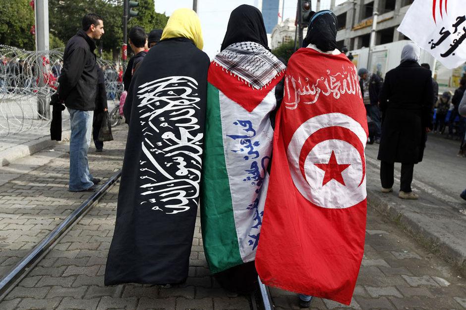 Meisjes (van links naar rechts) met vlaggen van het salafisme, de Palestijnen en Tunesië vieren de tweede verjaardag van de Tunesische revolutie op de Avenue Habib Bourguiba in Tunis.