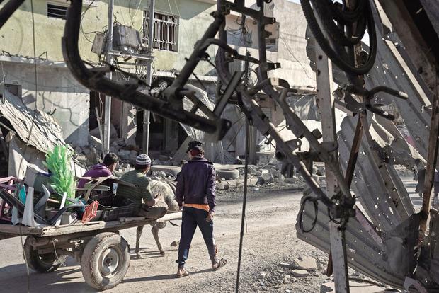 Au long d'artères dévastées (ici, les vestiges d'une boutique de deux-roues), la vie reprend son cours dans le quartier d'Al-Quds, libéré trois jours auparavant.