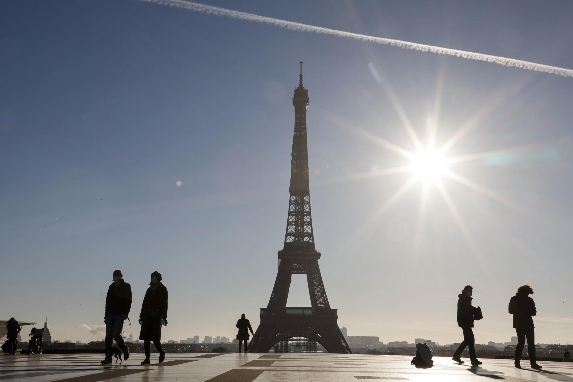 Des passants devant la Tour Eiffel, sur la place du Trocadéro à Paris, le 18 novembre 2020, lors d'un deuxième confinement visant à contenir la propagation de la pandémie de Covid-19.