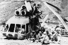 Des moudjahidines déjeunent à côté d'un hélicoptère soviétique abattu au cours d'une attaque menée par les rebelles durant la guerre d'Afghanistan de 1979 -1989. 