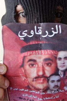 Un insurgé irakien tient une affichette promettant une récompense pour toute information qui conduirait à la capture de Zarqaoui dans la ville de Falluja en 2004. On peut y lire en arabe : 
