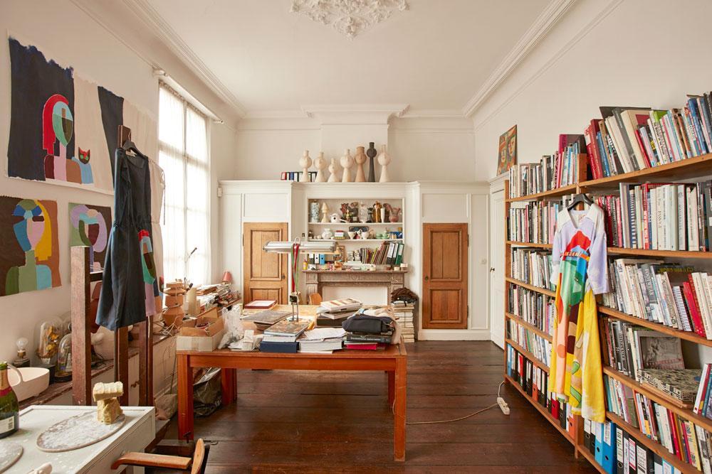 In Dirks atelier raken mode en kunst elkaar. Rechts een jurk uit zijn nieuwe collectie, daarachter een uitgebreide bibliotheek met kunstboeken.