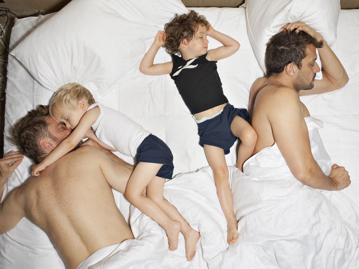 Bart Heynen met zijn man Rob en tweelingzonen Ethan en Noah, 's ochtends vroeg in bed.