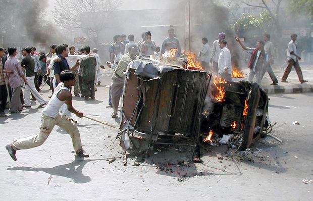 Un manifestant indien frappe un pousse-pousse en feu avec un bâton à Ahmedabad, la ville principale de l'ouest de l'état de Gujarat, le 28 février 2002. Des foules enervées se déchaînent, détruisant les biens des musulmans en représailles d'une attaque brûlant à vif 58 activistes hindous et leurs enfants dans un train.