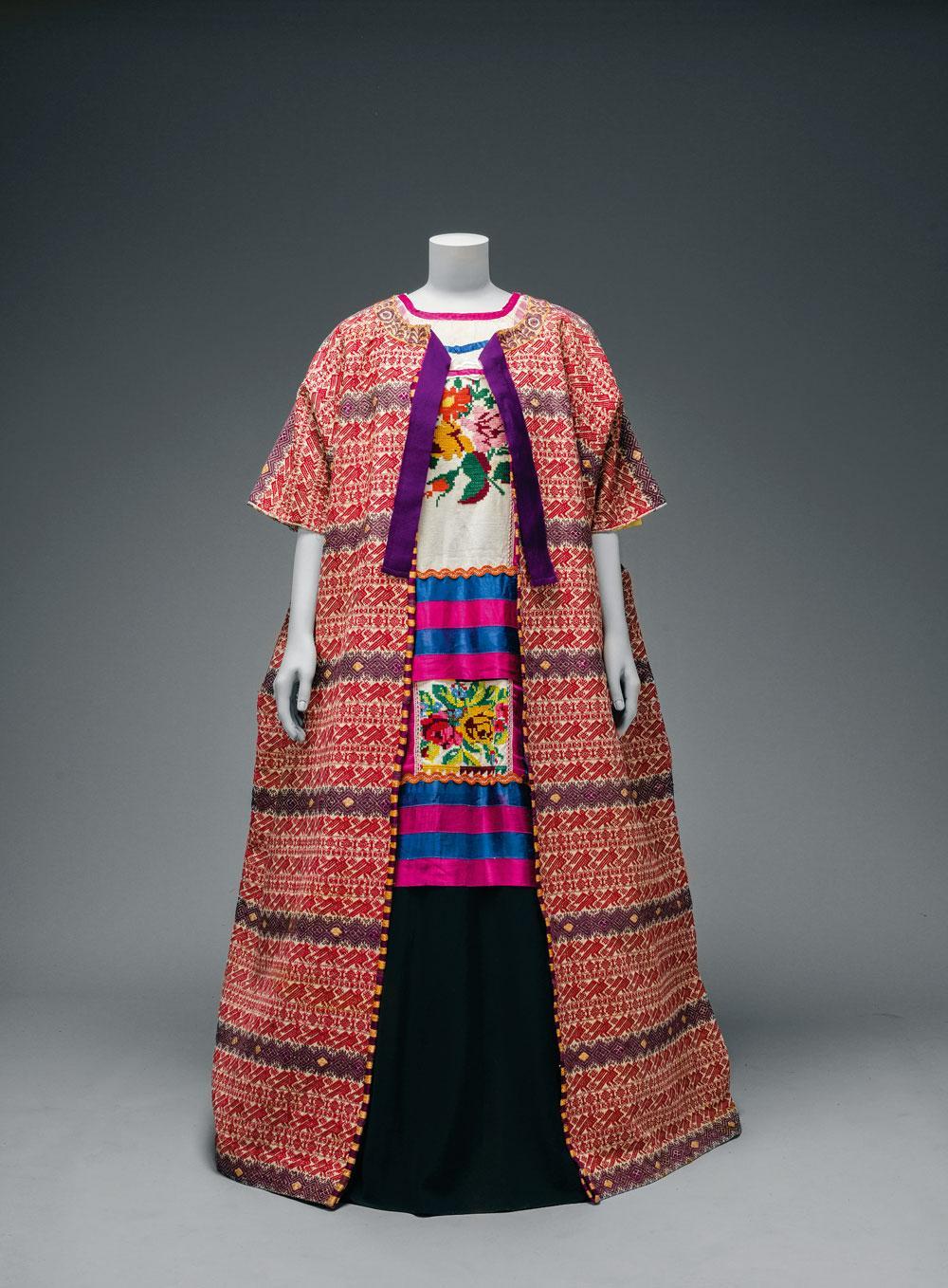Katoenen mantel uit Guatemela, gecombineerd met een blouse uit Oaxaca en een enkellange rok, in het V&A Museum.