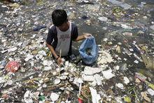 Een kleine jongen verzamelt plastic afval om te verkopen.