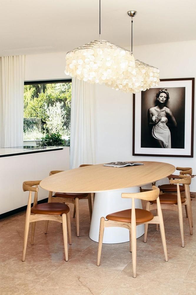 Naast het kookeiland staan Elbow Chairs van Carl Hansen rond Ufo, een tafel van Emmemobili. De gordijnen werden op maat gemaakt bij Maîtresse de Maison in Saint-Tropez. De foto is werk van Vincent Peeters.